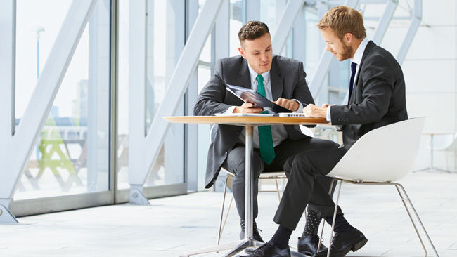 Zwei junge Männer sitzen an einem Tisch und sprechen über Aesculap Aeos®